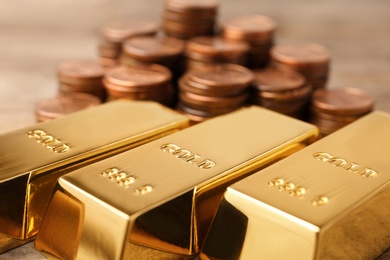 Photo of Shiny gold bars and coins on table, closeup