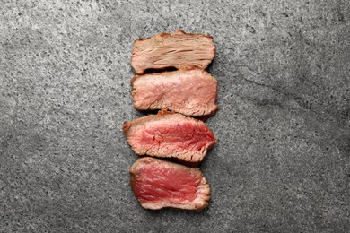 Photo of Delicious sliced beef tenderloin with different degrees of doneness on grey table, top view