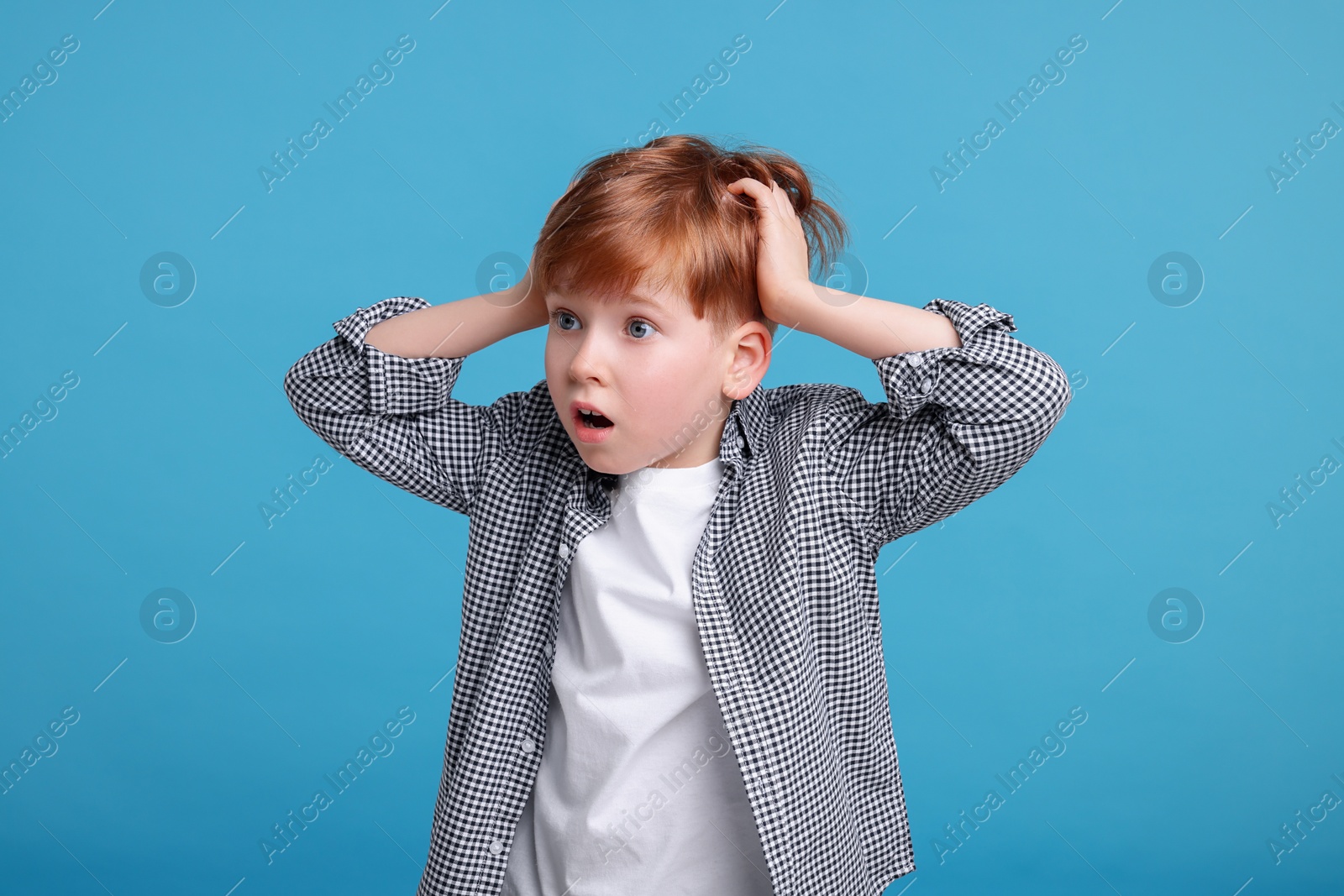 Photo of Surprised little boy on light blue background