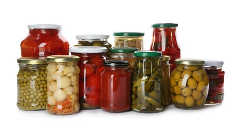 Glass jars with different pickled vegetables and mushrooms on white background