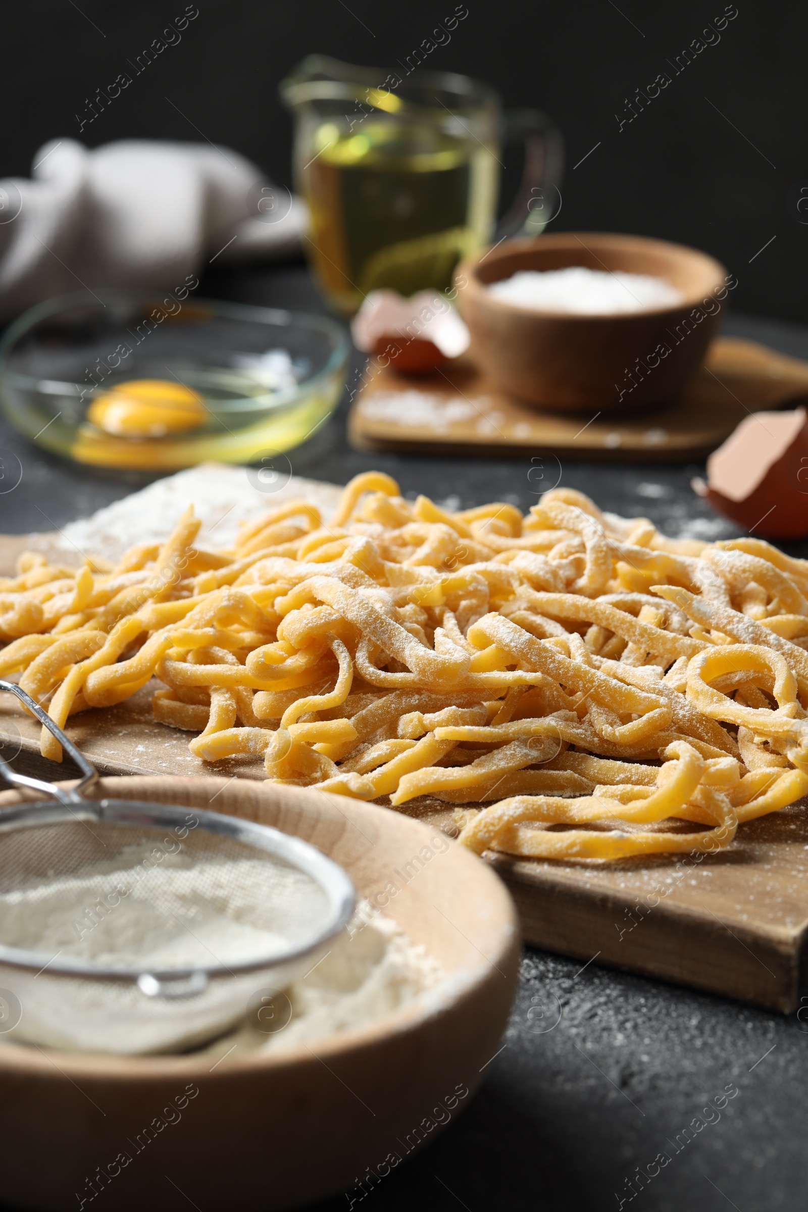 Photo of Board with homemade pasta and ingredients on dark table