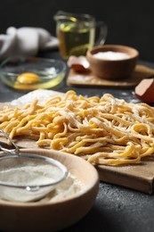 Board with homemade pasta and ingredients on dark table