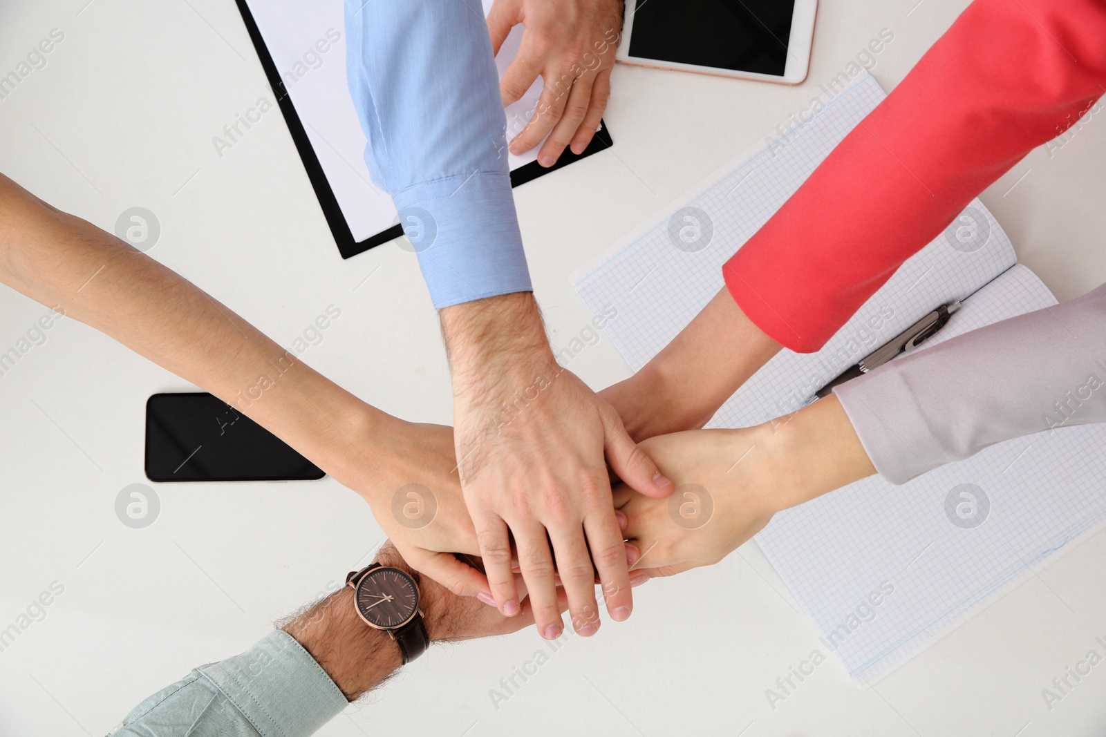 Photo of Young people holding hands together over table, top view. Team victory concept