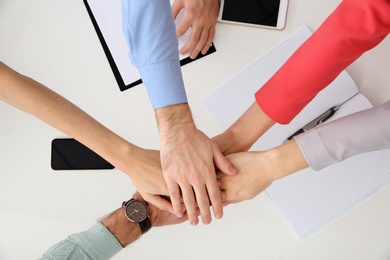 Young people holding hands together over table, top view. Team victory concept