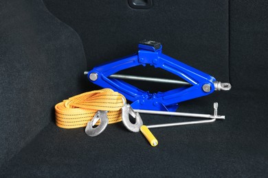 Photo of Scissor jack and towing strap in trunk. Car safety equipment
