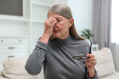 Overwhelmed woman with glasses suffering at home