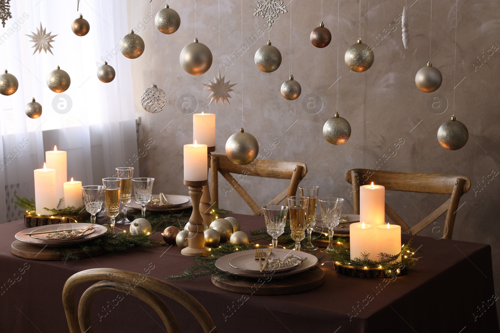 Photo of Christmas table setting with burning candles and festive decor