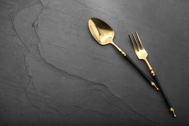 Photo of Shiny fork and spoon on black table, flat lay. Space for text