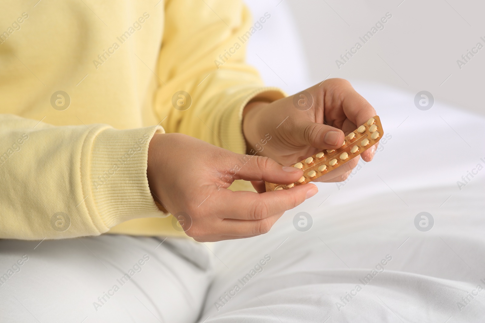 Photo of Woman taking blister of oral contraception pill in bedroom, focus on hands