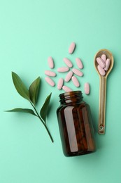 Vitamin pills, bottle, spoon and branch on mint color background, flat lay