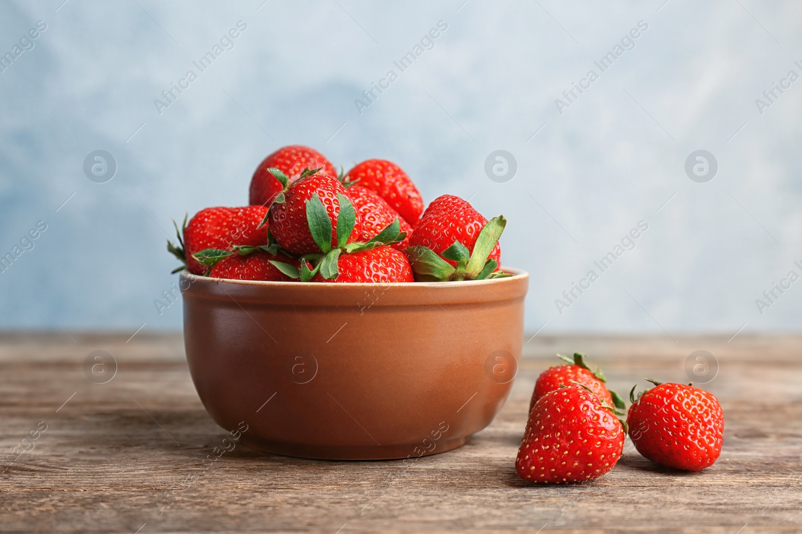 Photo of Bowl with ripe red strawberries on wooden table