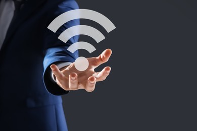 Image of Man holding Wi Fi symbol in hand on dark grey background, closeup