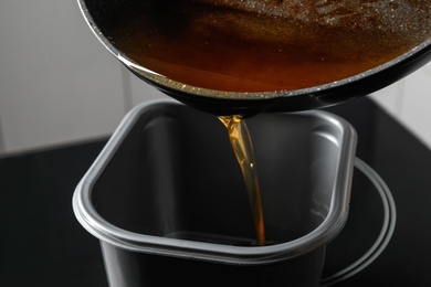 Pouring used cooking oil from frying pan into container, closeup