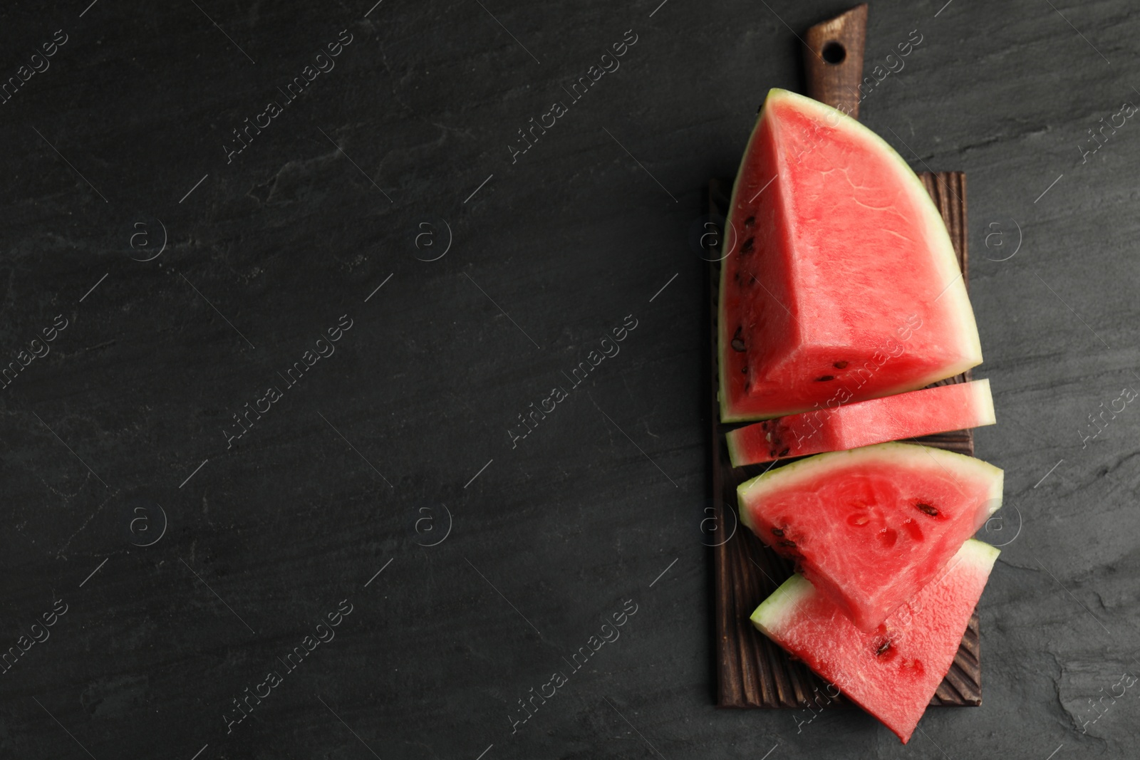 Photo of Slices of ripe juicy watermelon on black table, top view. Space for text