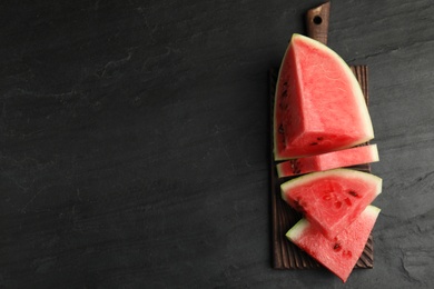 Photo of Slices of ripe juicy watermelon on black table, top view. Space for text