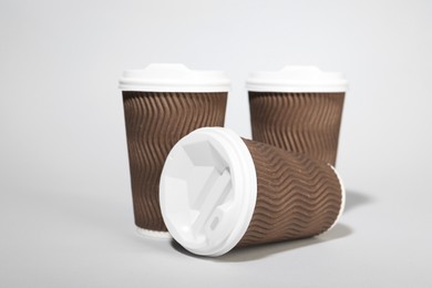 Photo of Paper cups with white lids on light gray background. Coffee to go