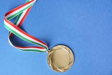 Gold medal on blue background, top view. Space for design