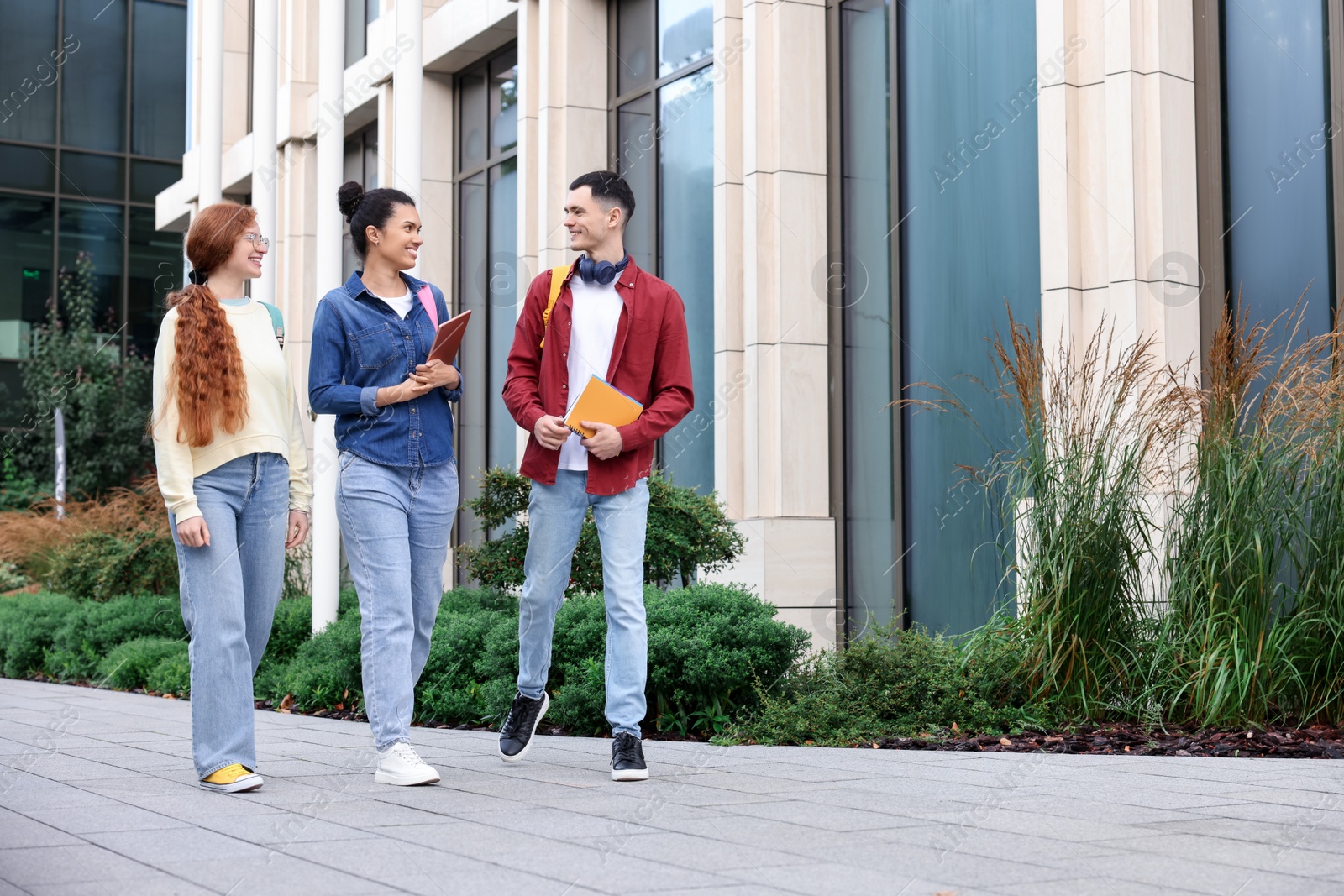 Photo of Group of happy young students walking together outdoors