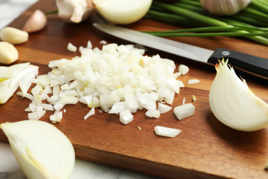 Photo of Board with cut onion and garlic on table, closeup