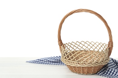 Photo of Empty wicker basket and cloth on wooden table against white background, space for text. Easter holiday