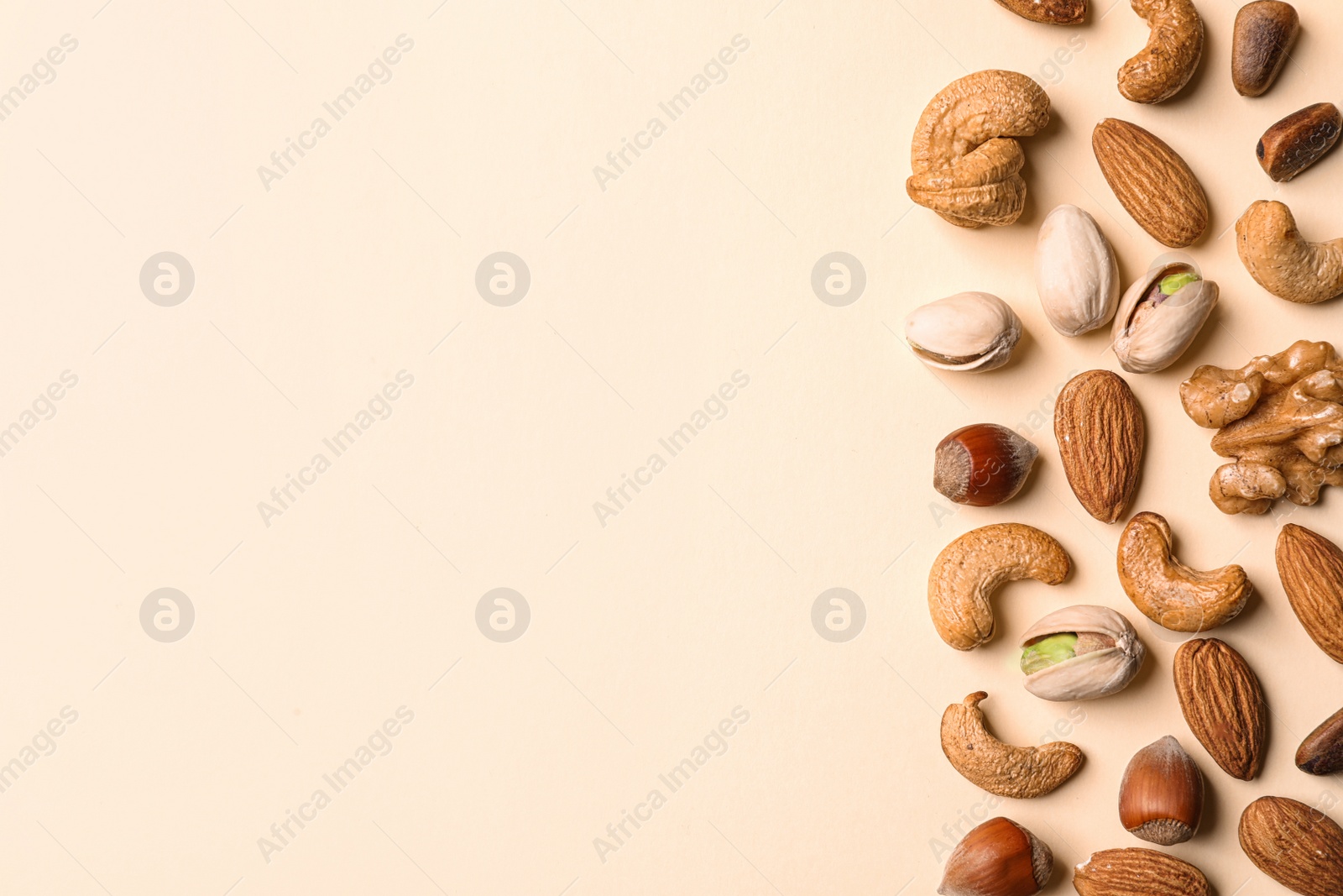 Photo of Flat lay composition with organic mixed nuts and space for text on color background