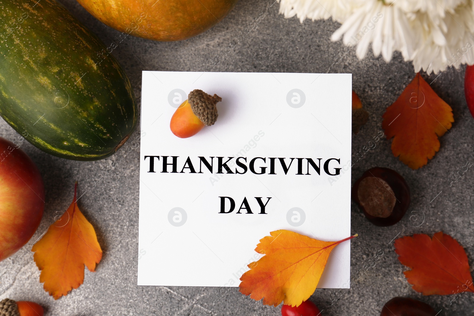 Photo of Thanksgiving day, holiday celebrated every fourth Thursday in November. Flat lay with paper card and autumn leaves on grey table