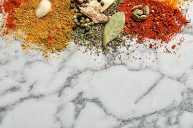 Different aromatic spices on marble background, top view with space for text