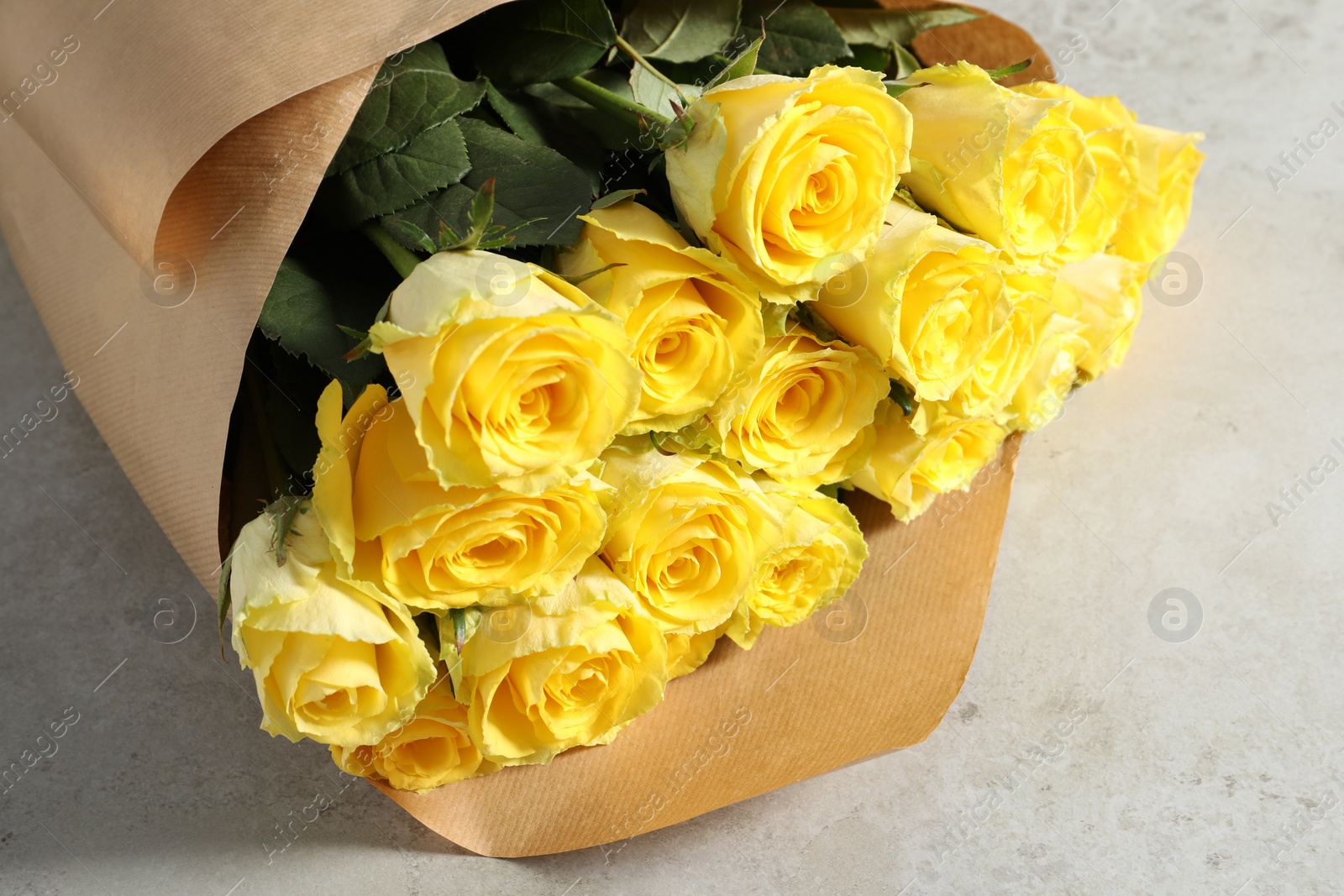 Photo of Beautiful bouquet of yellow roses on light grey table, closeup