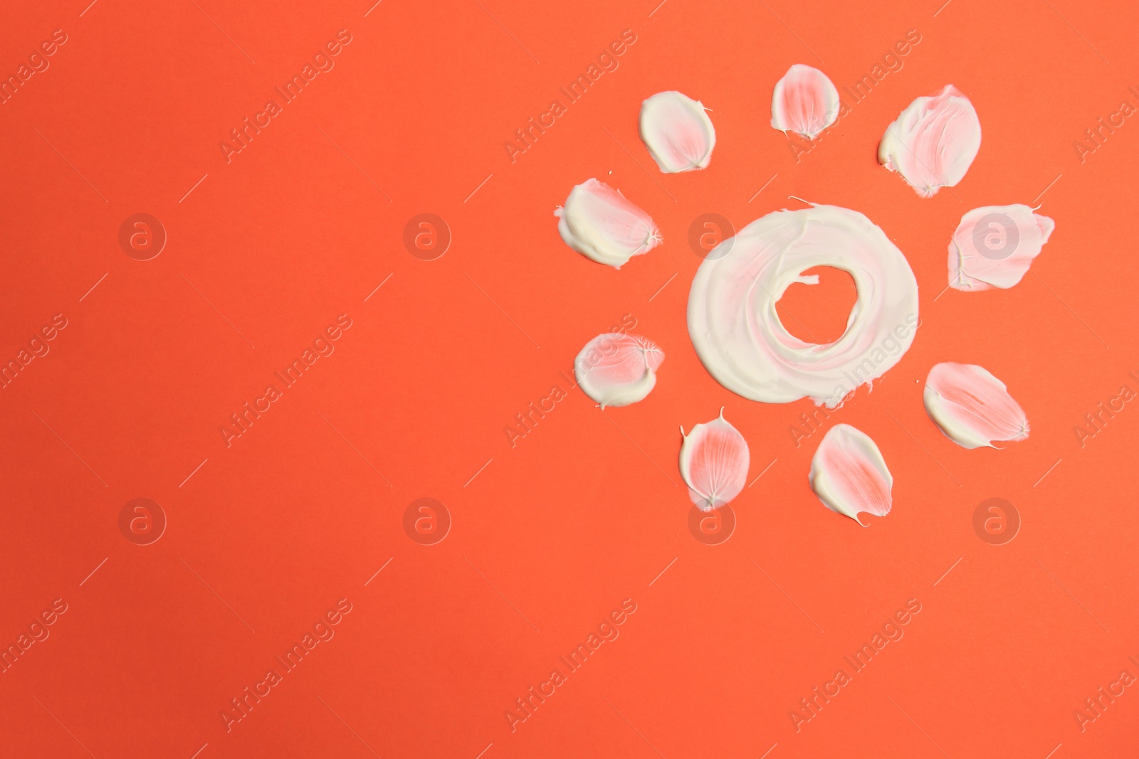 Photo of Sun drawn with sunscreen on coral background, top view and space for text. Skin protection