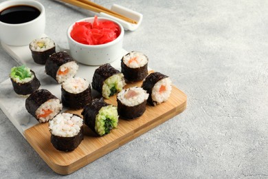 Tasty sushi rolls served on grey table. Space for text