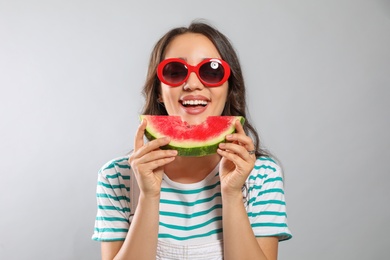 Photo of Beautiful young woman with watermelon on grey background