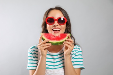 Beautiful young woman with watermelon on grey background