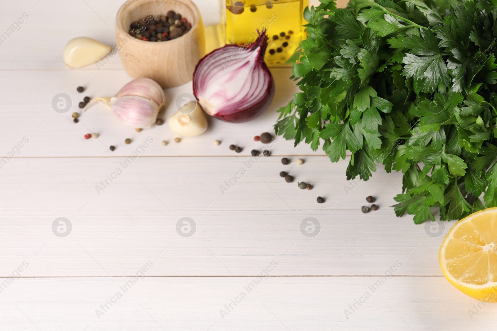 Photo of Fresh green parsley, spices and other products on white wooden table, space for text