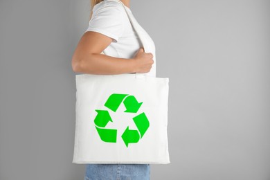 Woman holding bag with recycling symbol on grey background