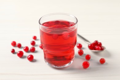 Photo of Tasty cranberry juice in glass and fresh berries on white wooden table, closeup