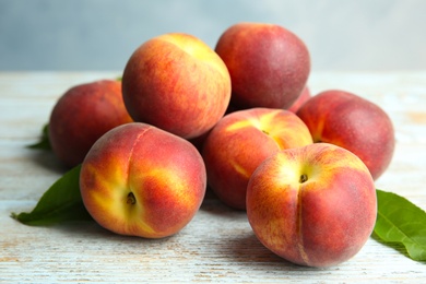 Photo of Pile of fresh peaches and leaves on wooden table