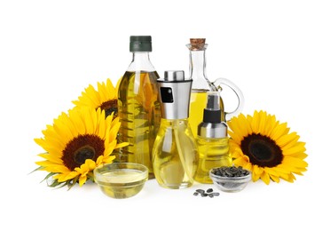 Bottles with cooking oil, sunflowers and seeds on white background