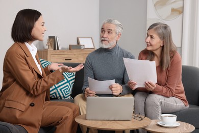 Photo of Insurance agent consulting elderly couple about pension plan in room