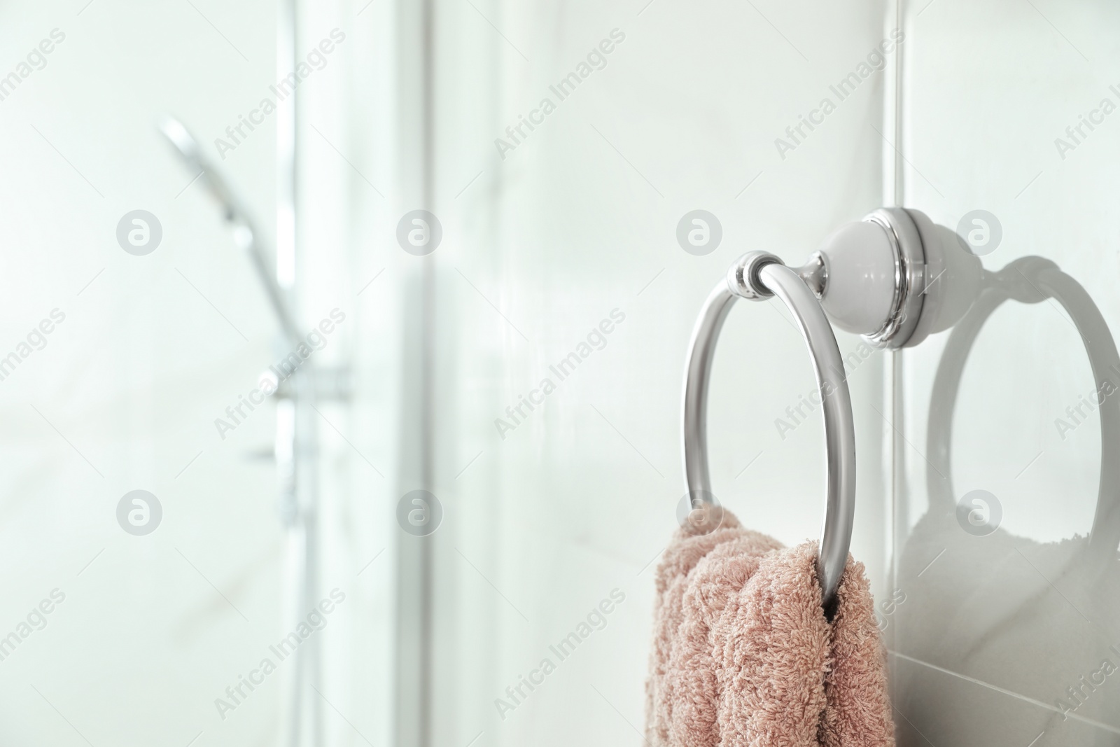 Photo of Holder with clean towel on light wall in bathroom