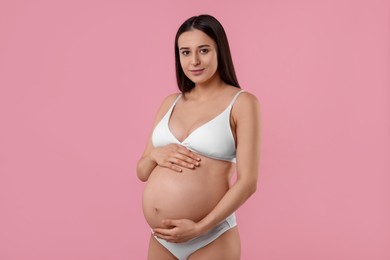 Beautiful pregnant woman in stylish comfortable underwear on pink background