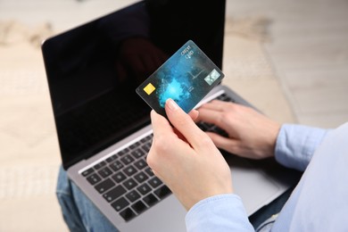 Photo of Online payment. Woman using credit card and laptop indoors, above view
