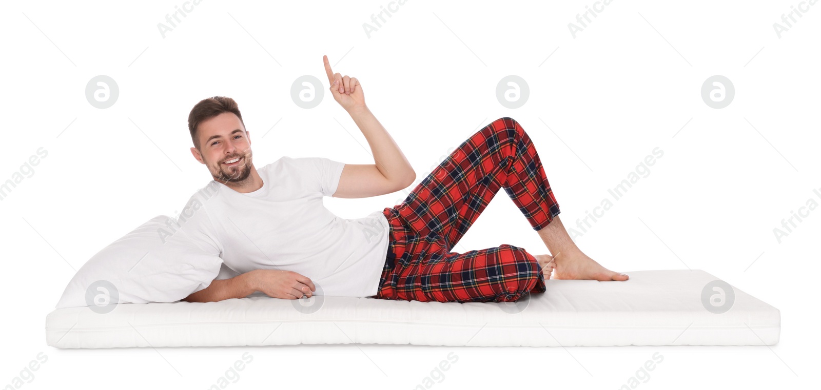 Photo of Man lying on soft mattress and pointing upwards against white background