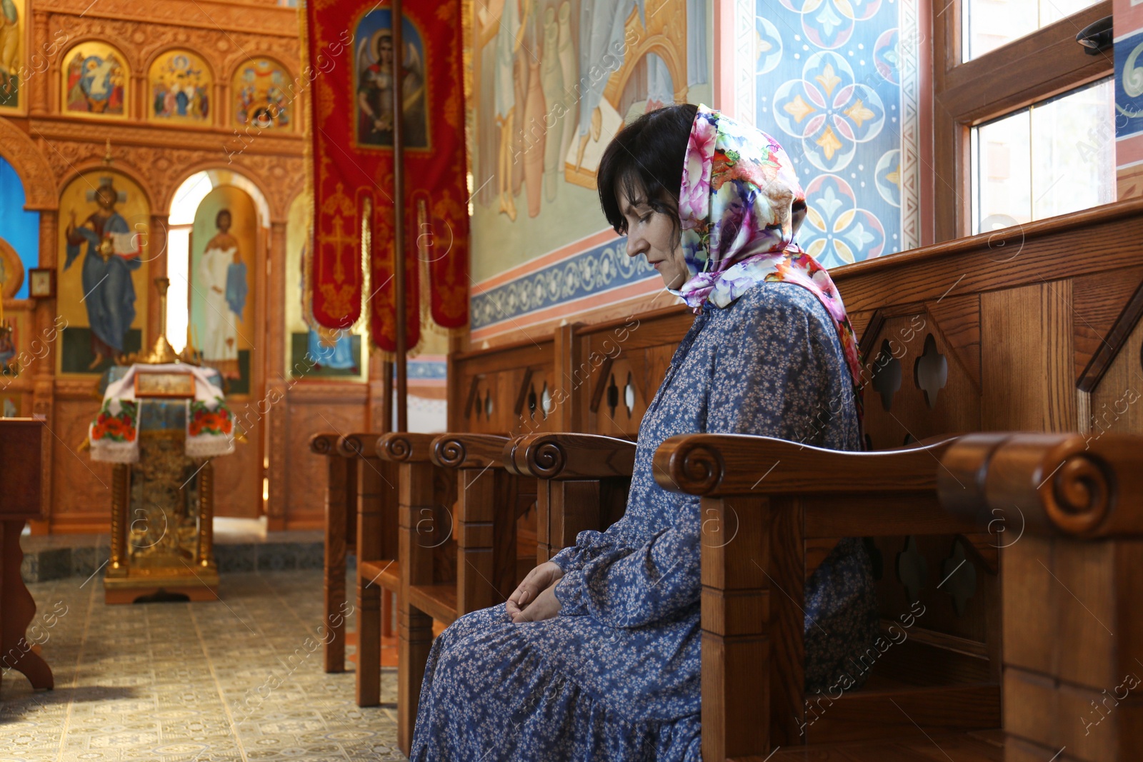 Photo of Mature woman sitting on wooden bench in church
