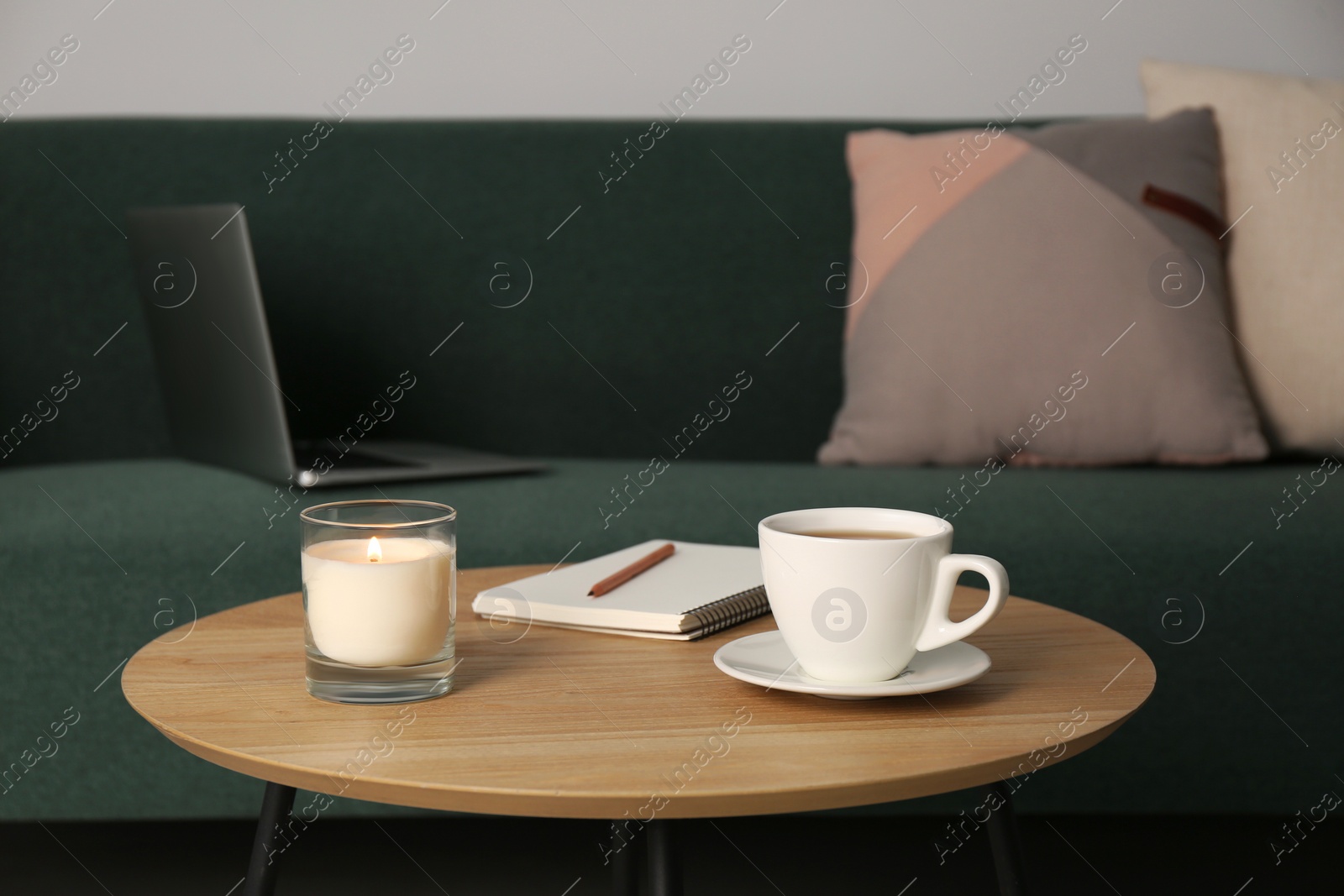 Photo of Wooden side table near sofa with laptop in room. Interior design