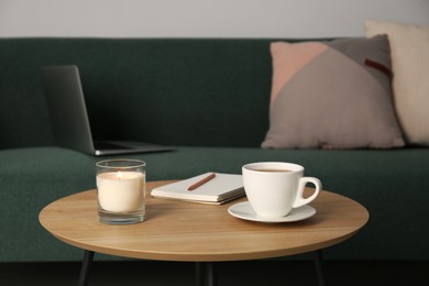 Wooden side table near sofa with laptop in room. Interior design