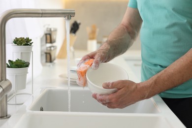 Photo of Man washing bowl above sink in kitchen, closeup