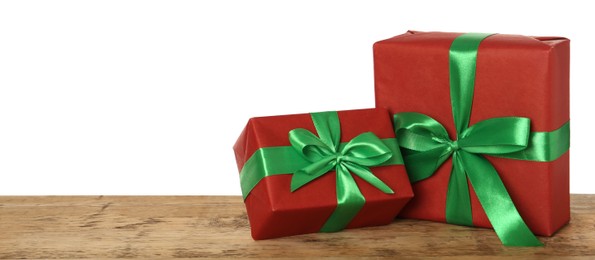Red gift boxes with green bows on wooden table against white background, space for text