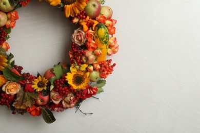 Photo of Beautiful autumnal wreath with flowers, berries and fruits on light grey background, top view. Space for text