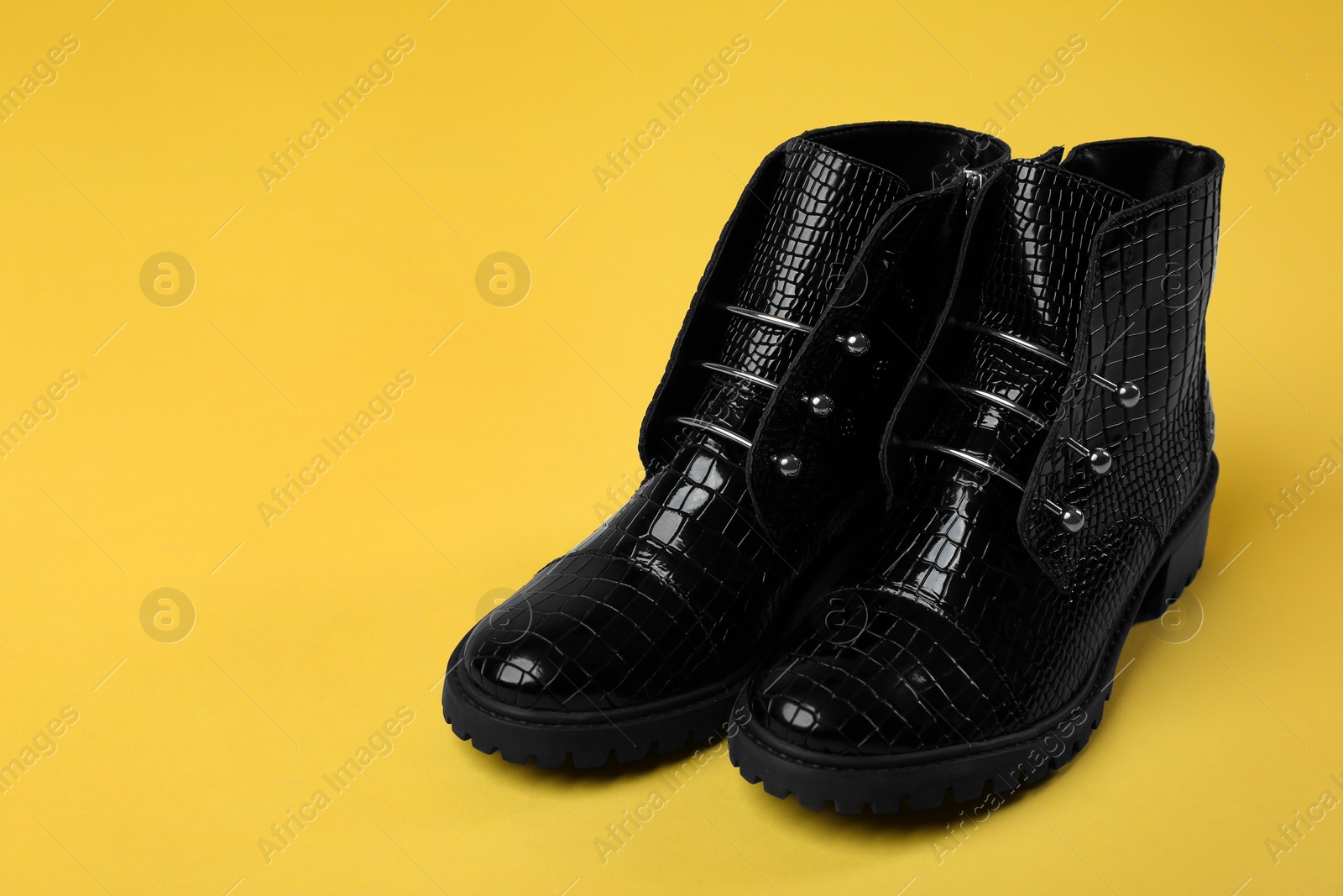 Photo of Pair of stylish ankle boots on yellow background