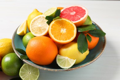 Photo of Different cut and whole citrus fruits on white wooden table